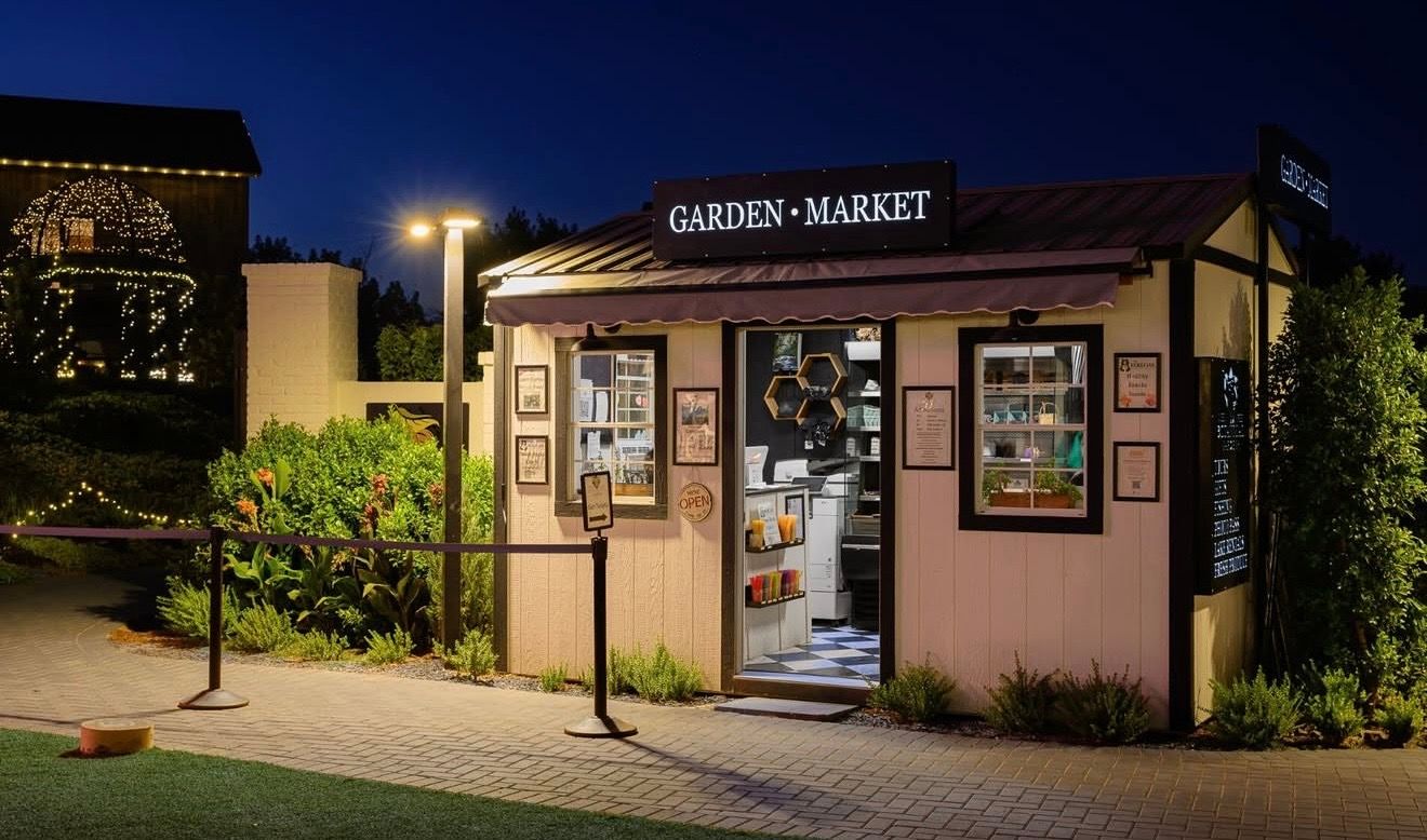 The Garden Market kiosk lit at night, the mill behind it in string lights